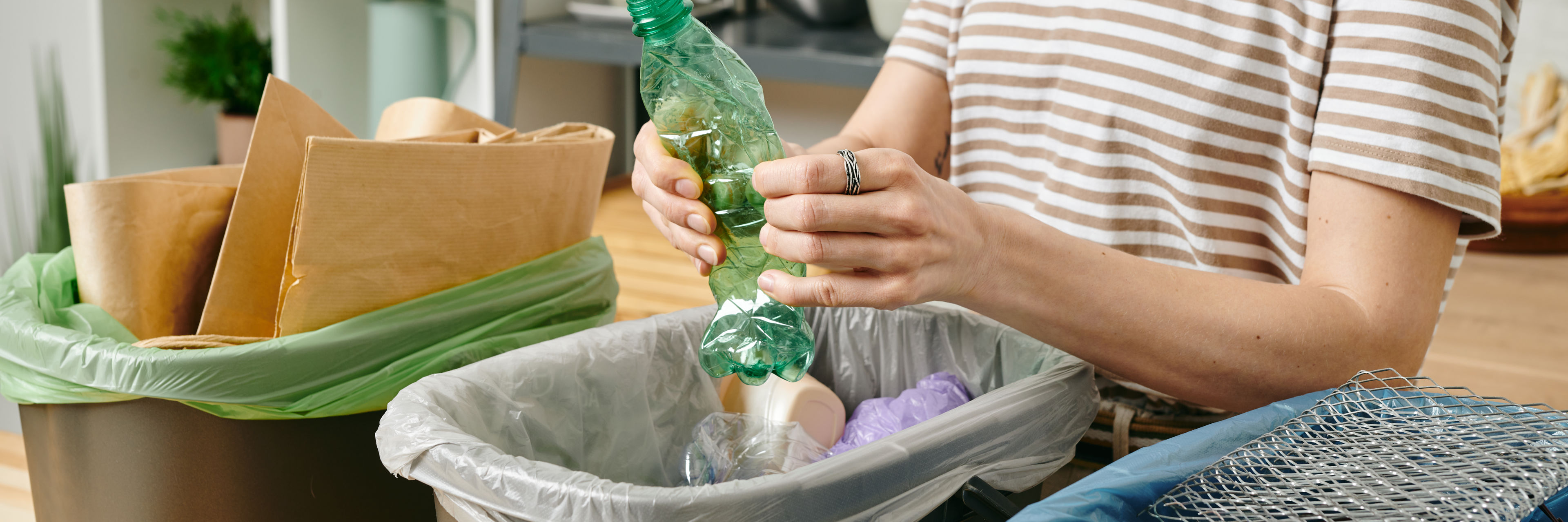 Kvinde sorterer affald ved køkkenbordet
