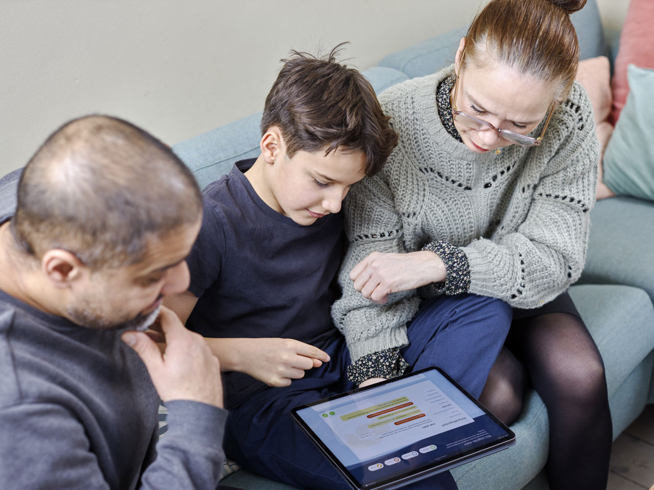 Forældre og barn der sidder i sofa og gennemgår Min Magiske Mave forløb på ipad